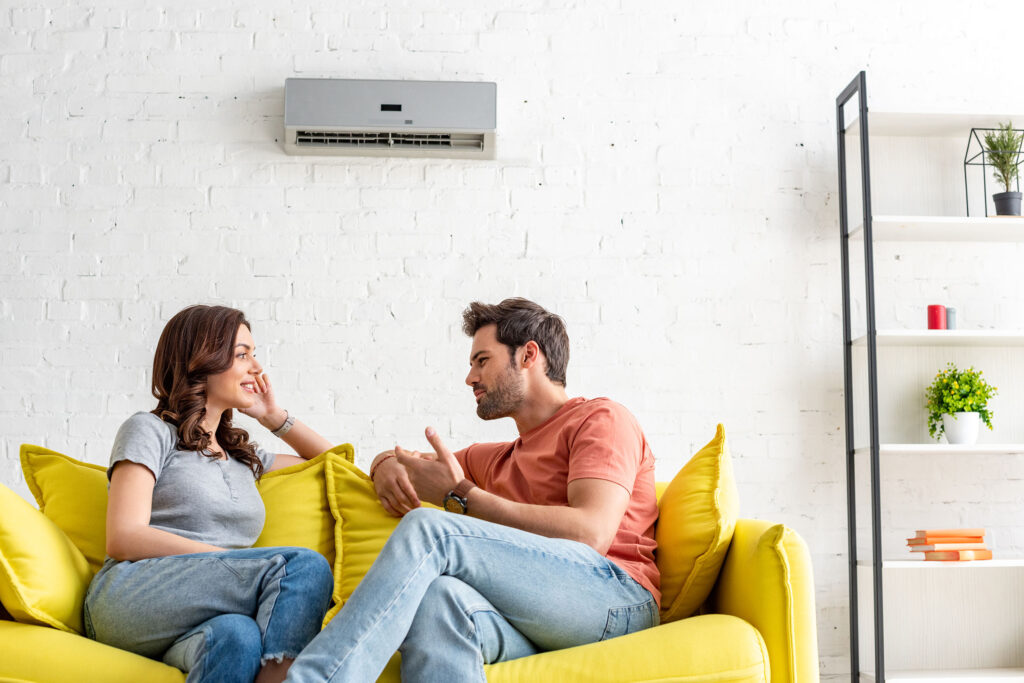 couple sitting in front of air conditioner